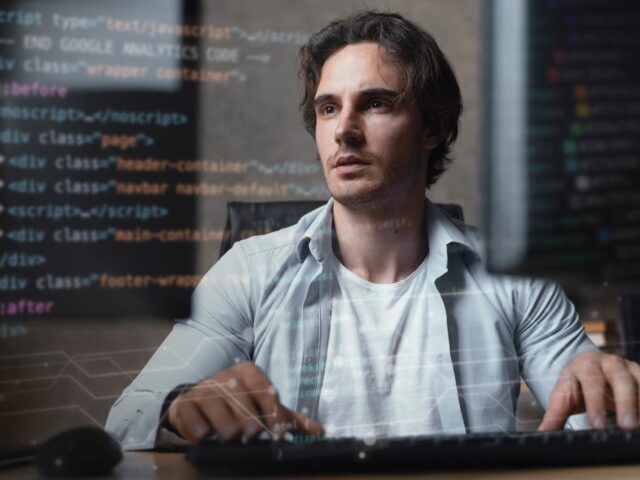 A man writes code while sitting at a computer