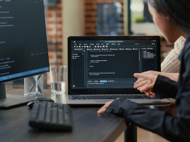 Team of programmers talking about algorithm running on laptop screen