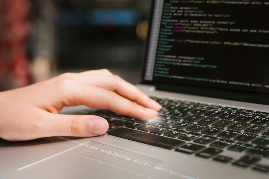 Human hand on laptop keyboard with program code