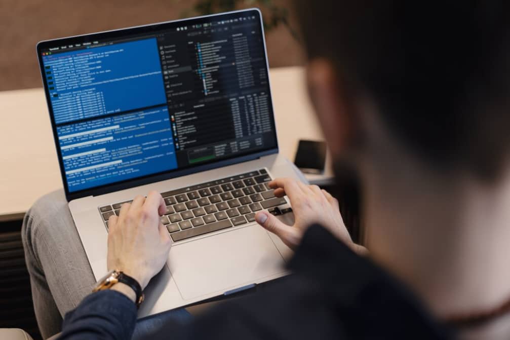An over-the-shoulder view of a person coding on a laptop