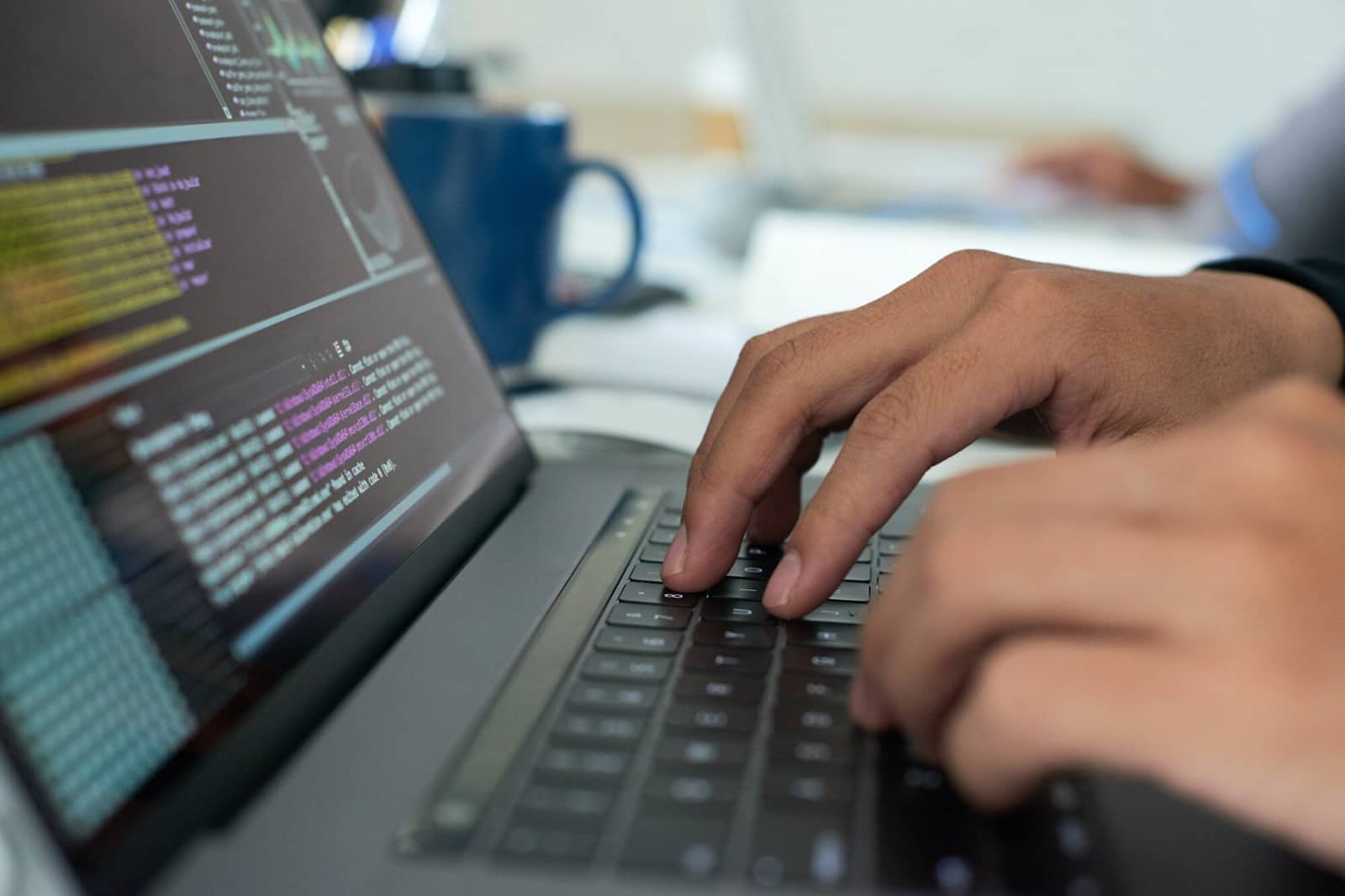 Hands writing code on laptop