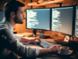 A man writes code on a computer and stares at the monitor