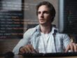 A man writes code while sitting at a computer
