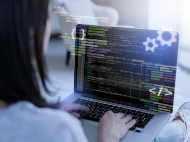 Girl writes code on a laptop, rear view