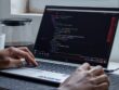 A man writes computer code on a laptop