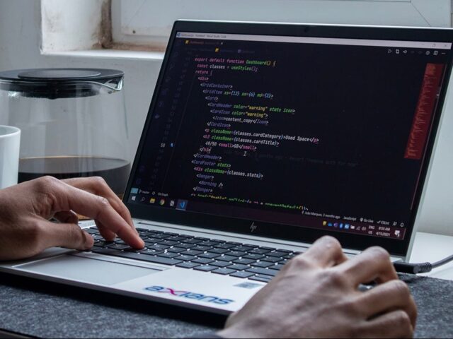 A man writes computer code on a laptop